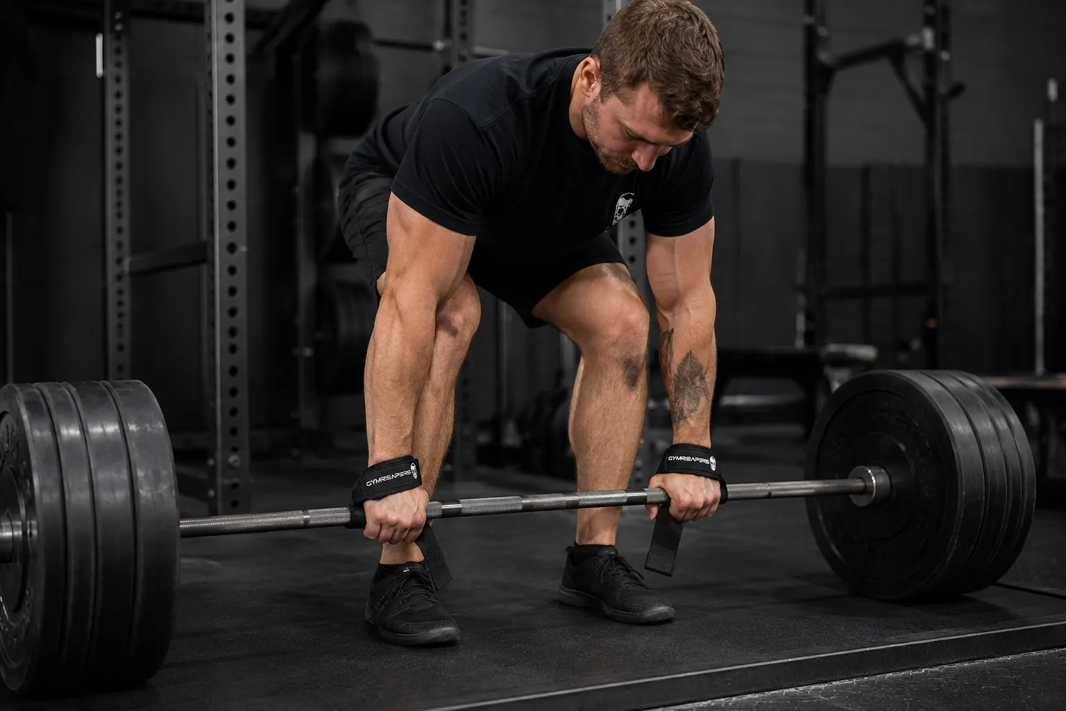Gymreapers lifting straps wrapped around a barbell before a heavy deadlift