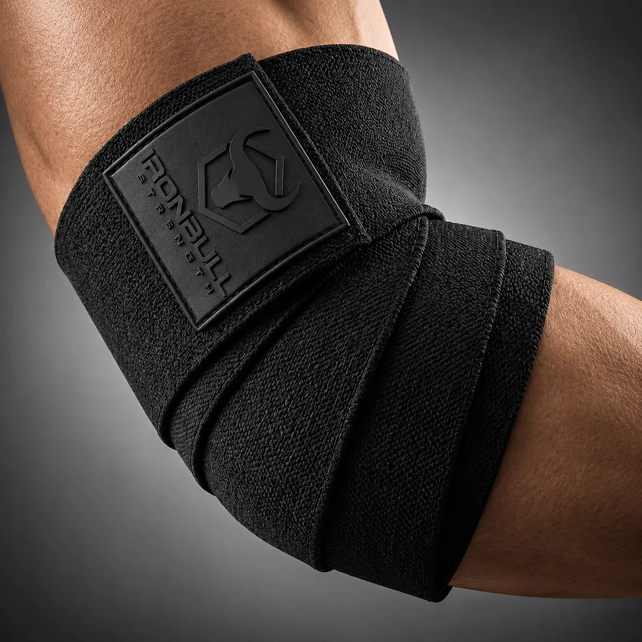 Iron Bull Strength black elbow wrap worn around the elbow